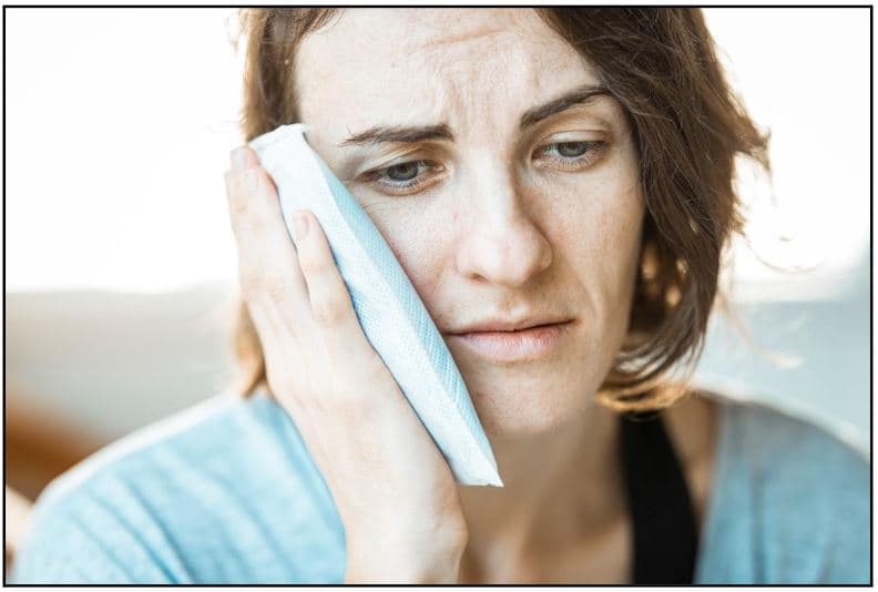 Woman holding her jaw due to TMJ pain