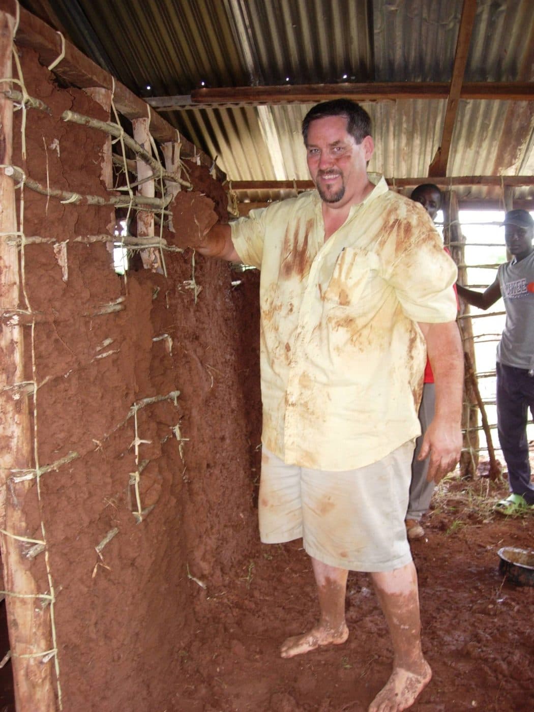 Dr. Johnson, covered in mud, helping build the wall of a home in Uganda