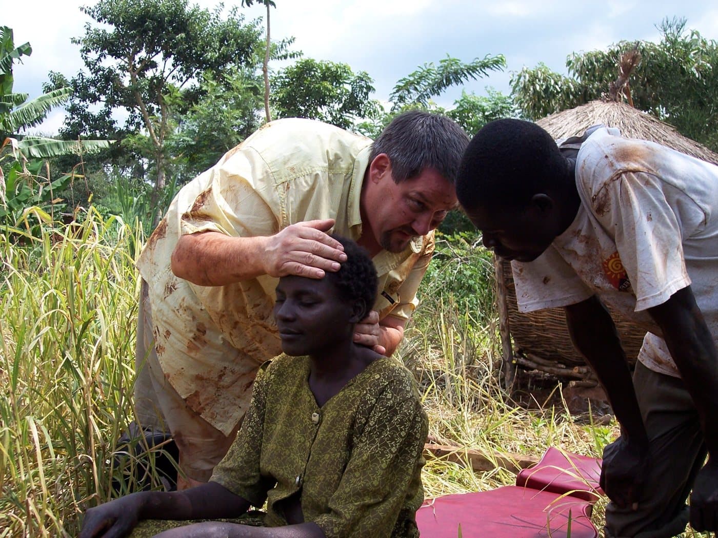 Dr. Johnson adjusting a woman outdoors on the mission field in Uganda