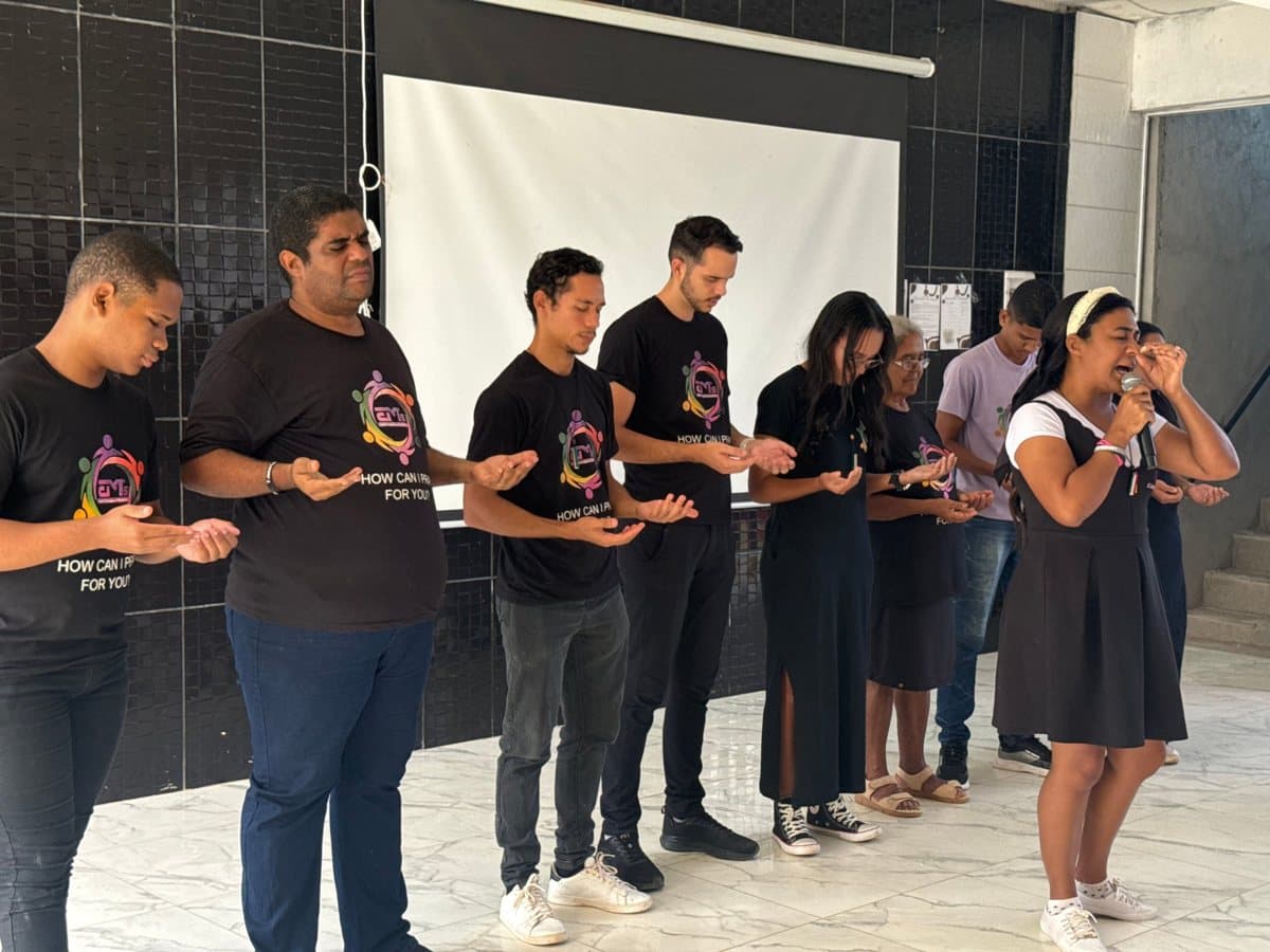 Em praying over the ministry teachers, who stand with open hands