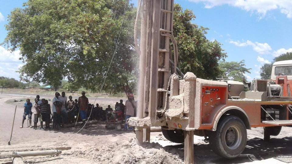 A well-drilling rig at work as villagers look on