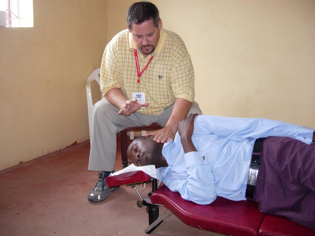 Dr. Johnson adjusting a man on a portable table during a mission trip