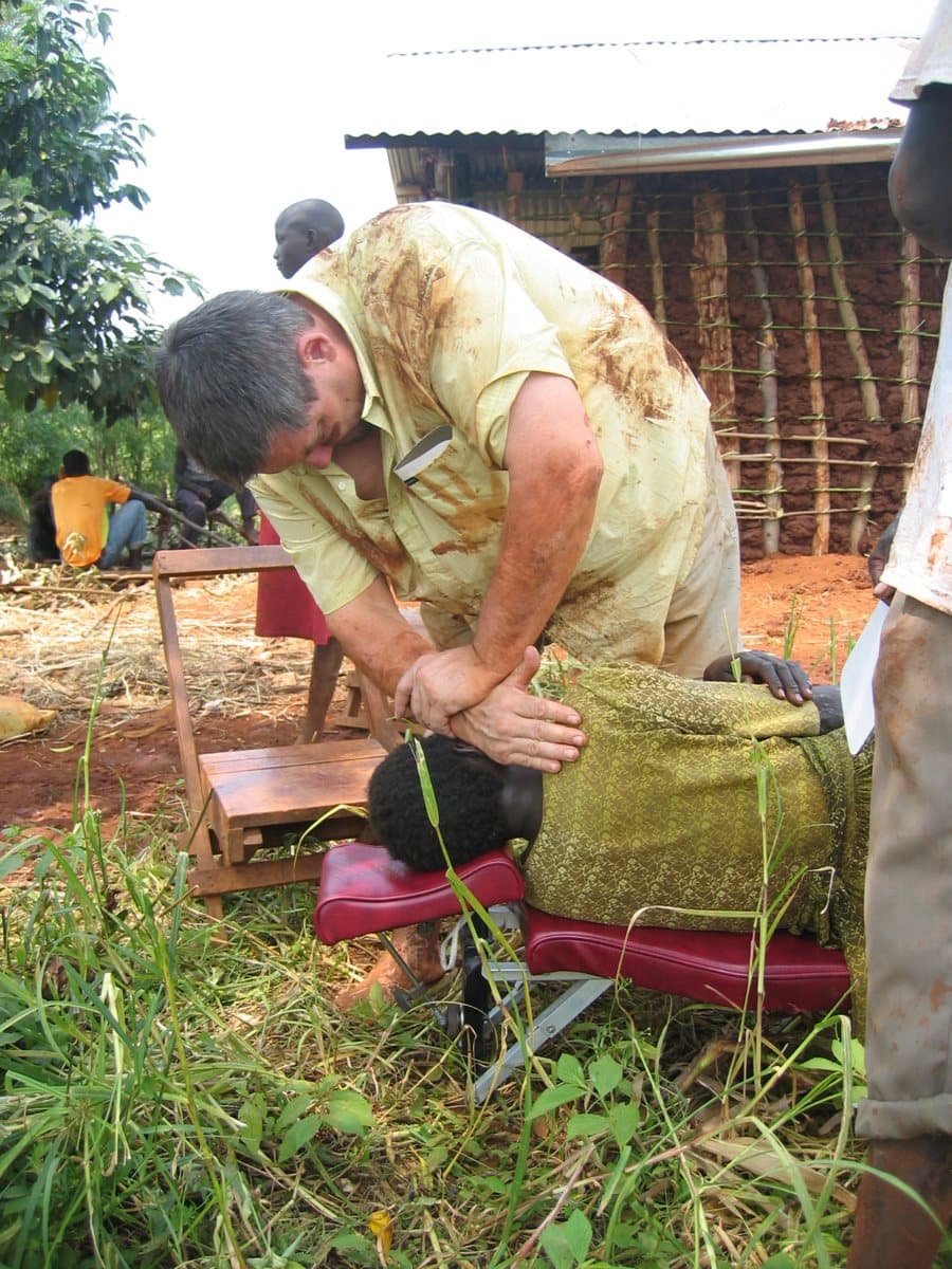 Dr. Johnson adjusting a woman on a portable table outdoors in Uganda